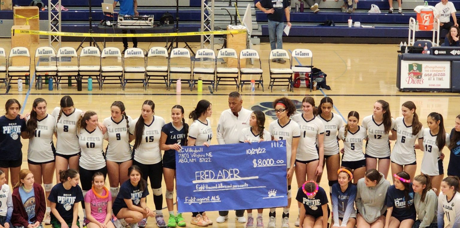 The La Cueva volleyball team presents a check to Fred Ader before Saturday's game.