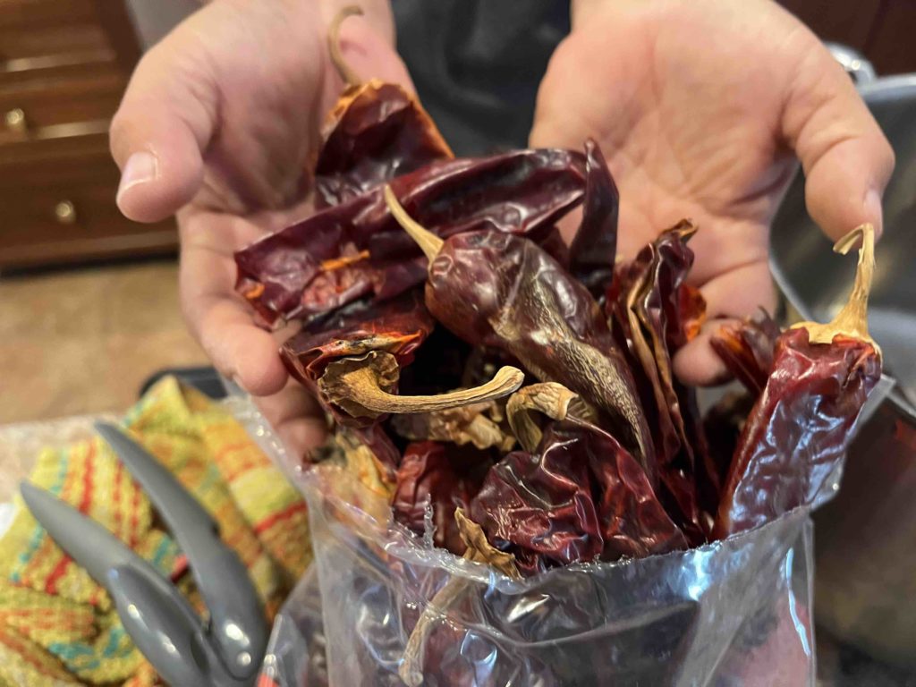 How to make New Mexico red chile sauce for the holidays Two hands holding New Mexico red chile pods.