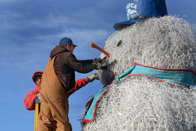 AMAFCA employees Mark Ramirez and James Moya add the face to the Tumbleweed Snowman along I-40 next to the offices of the AMAFCA in 2019. (Albuquerque file photo by Jim Thompson)