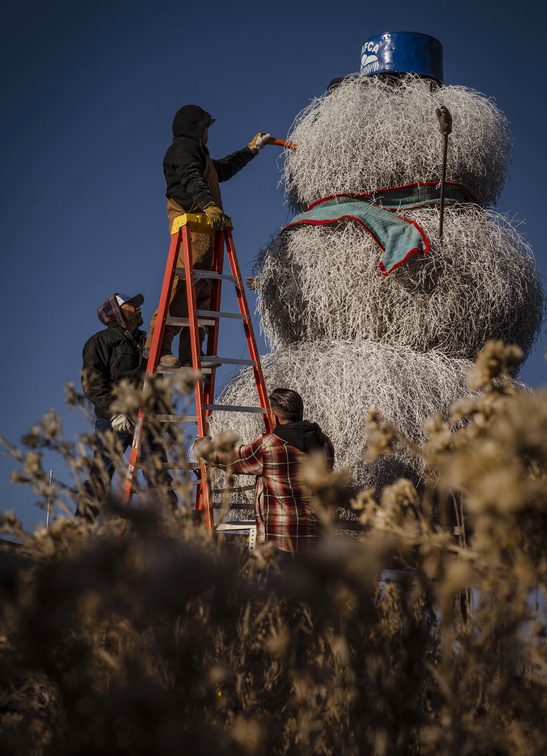AMAFCA employee James Moya secures the nose on the AMAFCA Tumbleweed Snowman along Interstate 40 in Albuquerque, N.M., on Tuesday, Nov. 29, 2022. The tradition began in 1995, marking this the 27th year of installing the local icon on Tumbleweed Tuesday, the Tuesday after the Thanksgiving holiday. (Chancey Bush/Albuquerque Journal)