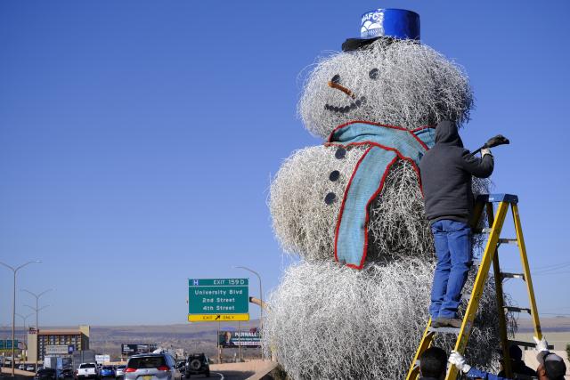 AMAFCA employee James Moya installs one of the arms on the Tumbleweed Snowman along I-40 near the Big I on Nov. 30, 2021. The structure has been a fixture for the last 27 years, bringing Holiday Cheers to motorists in a unique New Mexico way. (Albuquerque file photo by Adolphe Pierre-Louis)