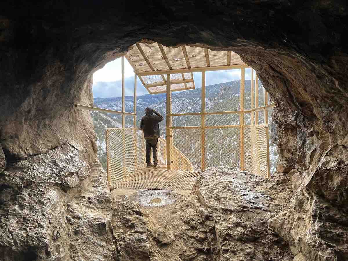 A visitor looks out toward Las Huertas Canyon from Sandia Cave, Dec. 30, 2022. (Scott Albright/Neighborhood Journal)